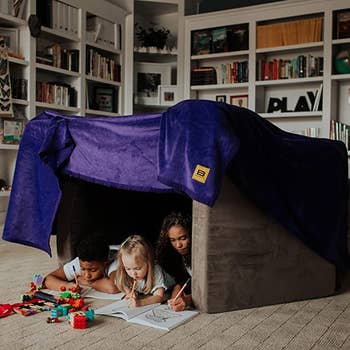 models using the purple blanket and couch cushions to make a fort