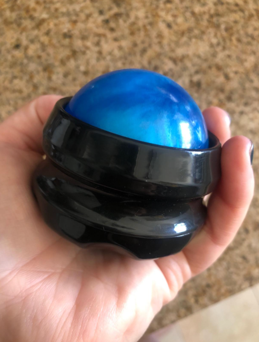 Reviewer holding a blue stress ball encased in a black gripper 