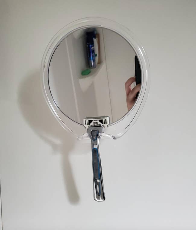 A round compact mirror attached to the wall 