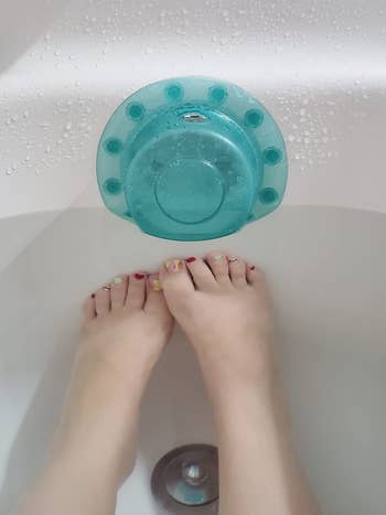 reviewer's feet near the blue overflow drain cover in a tub