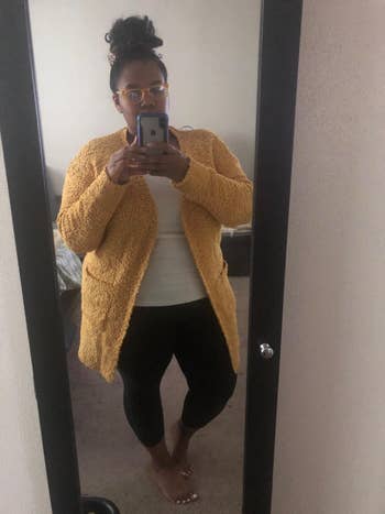 A reviewer taking a mirror selfie while wearing the cardigan in yellow