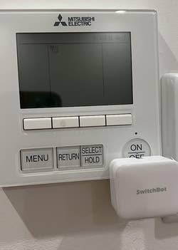 a reviewer photo of the SwitchBot mounted on a thermostat