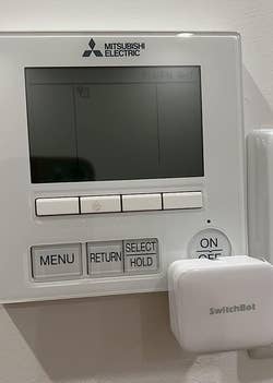 a reviewer photo of the SwitchBot mounted on a thermostat