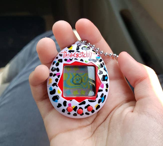 reviewer holding black, white, and red Tamagotchi