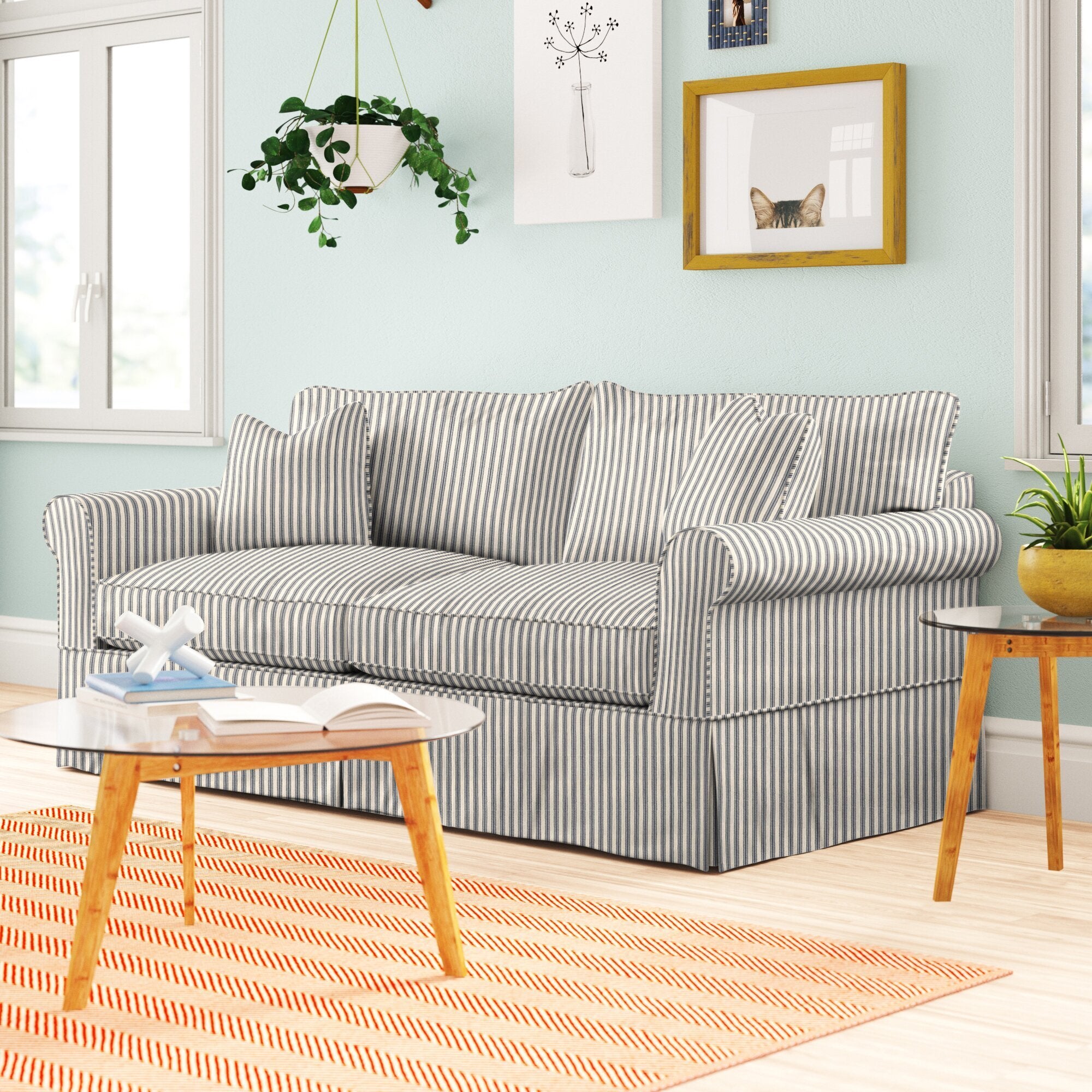 striped plush sofa with a slipcover that hits the bottom of the floor. it has armrests, back and bottom cushions, and matching decorative pillows. 
