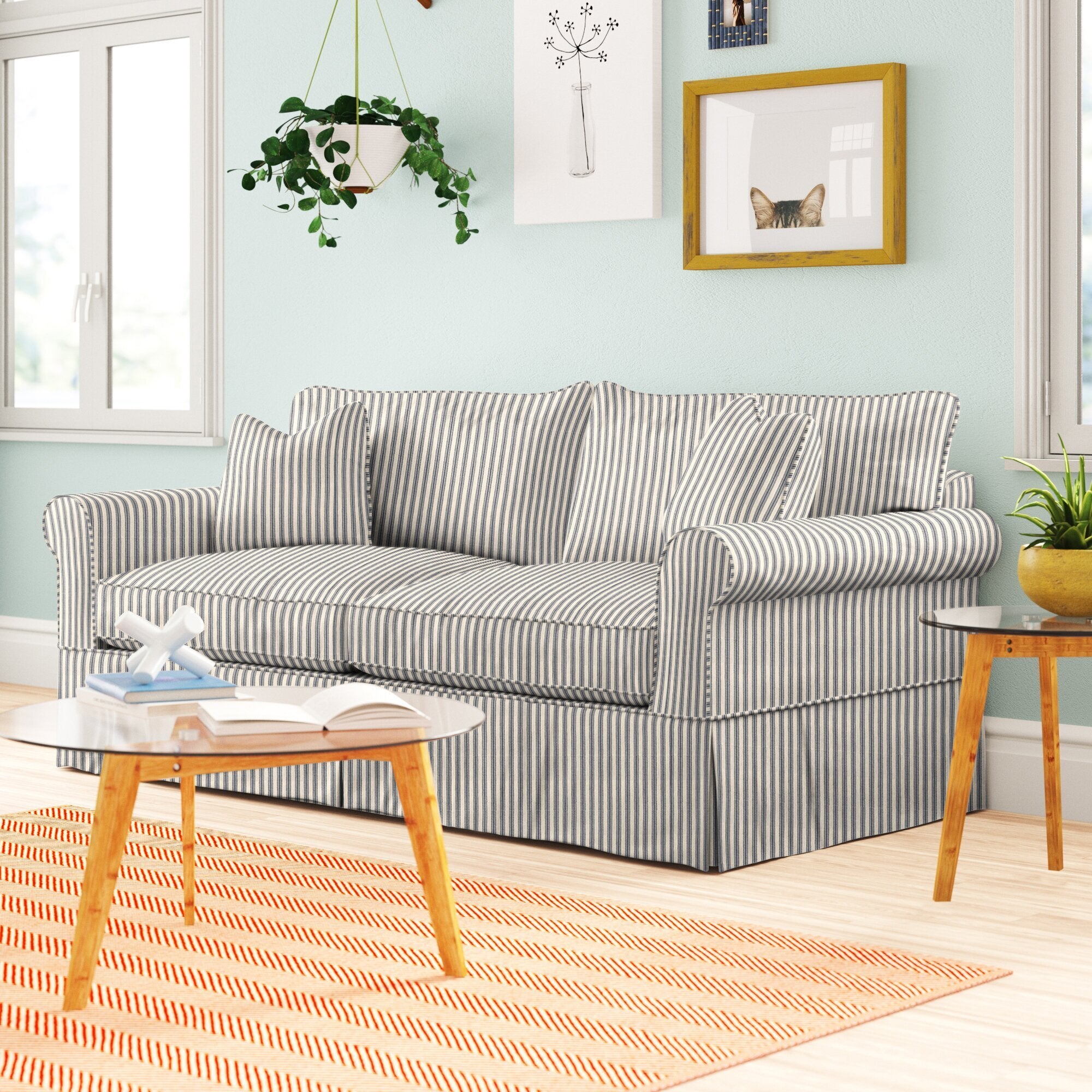 striped plush sofa with a slipcover that hits the bottom of the floor. it has armrests, back and bottom cushions, and matching decorative pillows.