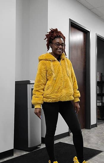 Image of reviewer in black leggings, a fluffy yellow jacket, and the sneakers in a matching yellow 