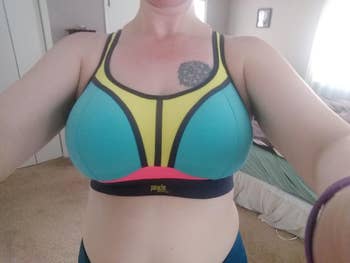 Person wearing a sporty, color-blocked bra, showing beforehand   plan  detail. The mounting  is simply a casual location  situation  with chamber  furnishings  visible