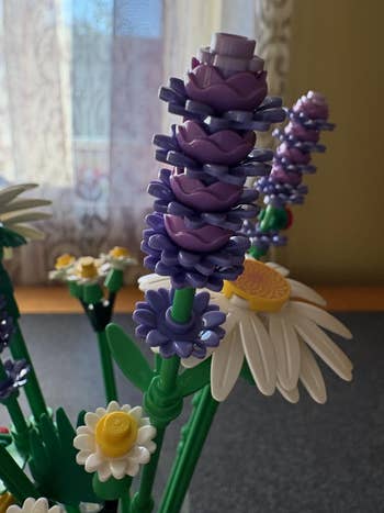 Lego flowers arranged successful  a vase, featuring purple and achromatic  blossoms with yellowish  centers