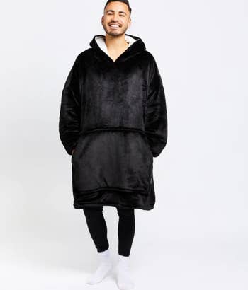 A model wearing a black oversized hoodie blanket