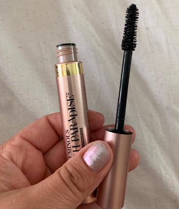 reviewer's hand holding the mascara tube and wand