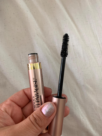 reviewer's hand holding the mascara tube and wand