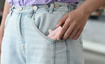 a model putting the portable charger into their pants pocket