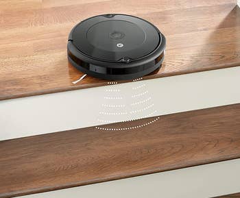 the roomba at the top of a staircase, with a graphic showing it can sense it's at a drop-off