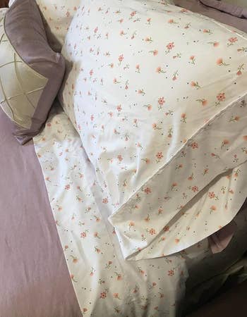 Bed with floral patterned sheets and a beige pillow on it
