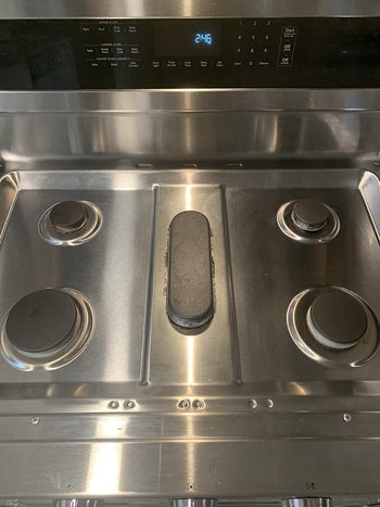 Reviewer photo of same stove without the caked on grease after using the Magic Eraser