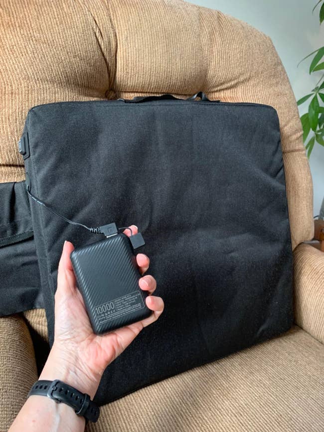 Person holding a portable charger with a cord successful  beforehand   of  the spot   cushion