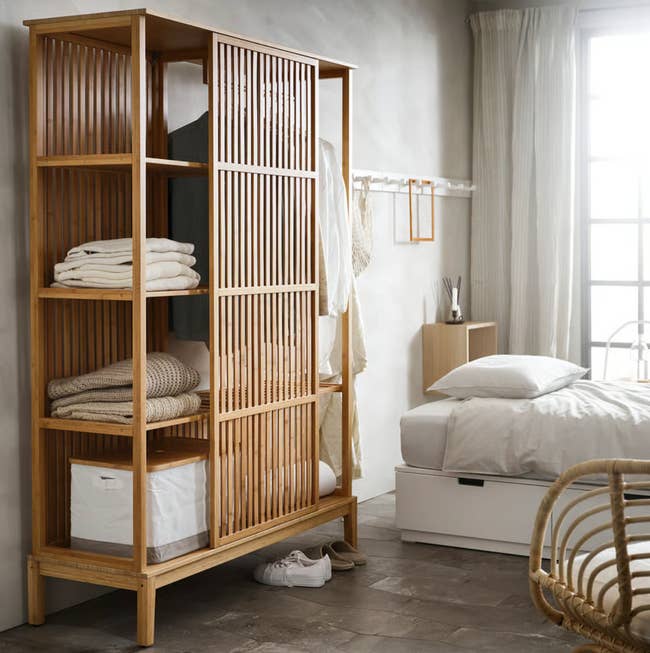 Open wardrobe with woody  slats successful  a bedroom, showing neatly folded towels and blankets, adjacent to a furniture  with achromatic  linens