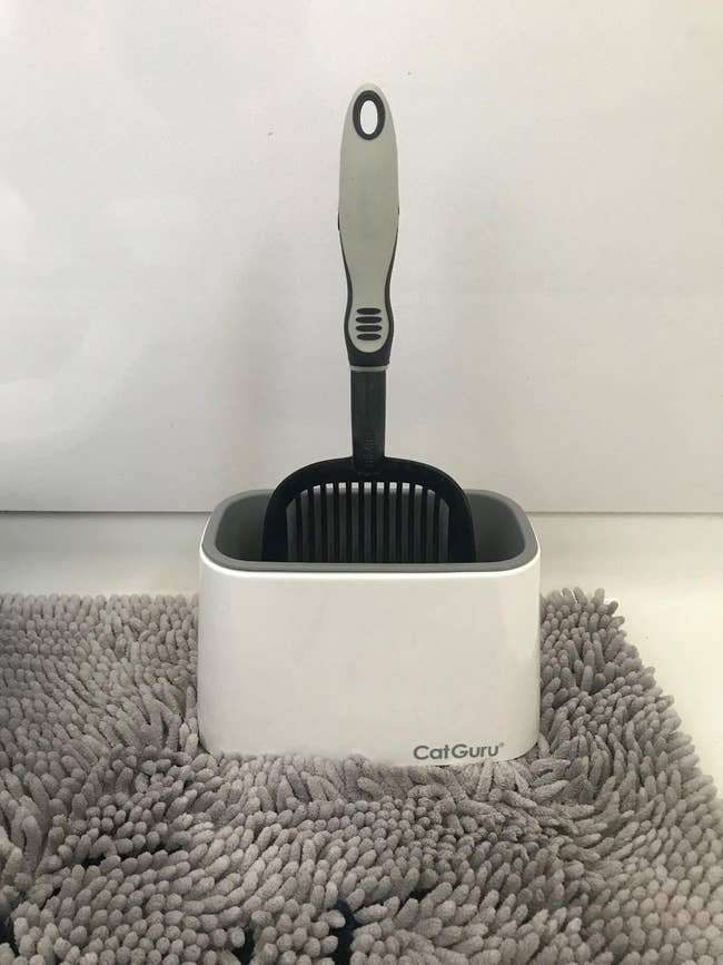 the white and gray plastic holder with a litter scoop inside it