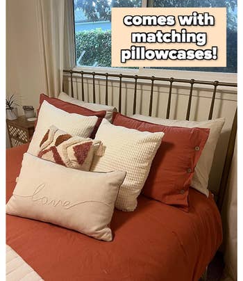 Bed with rust-colored bedding and assorted pillows; includes matching pillowcases