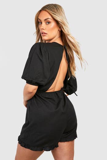 same model wearing the romper in black showing the open back