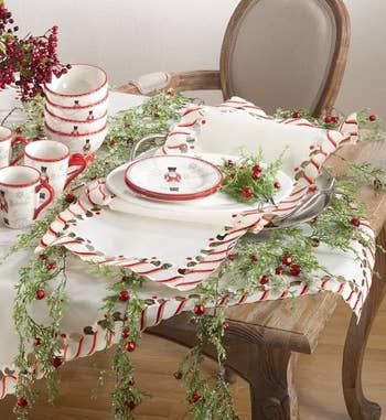the candy cane runner styled on a table with holly and festive plates and mugs