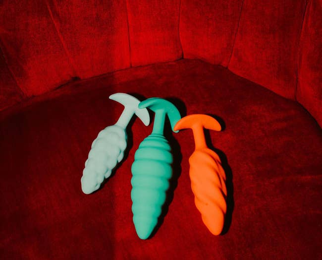 Light blue, green and orange butt plug side by side for size comparison