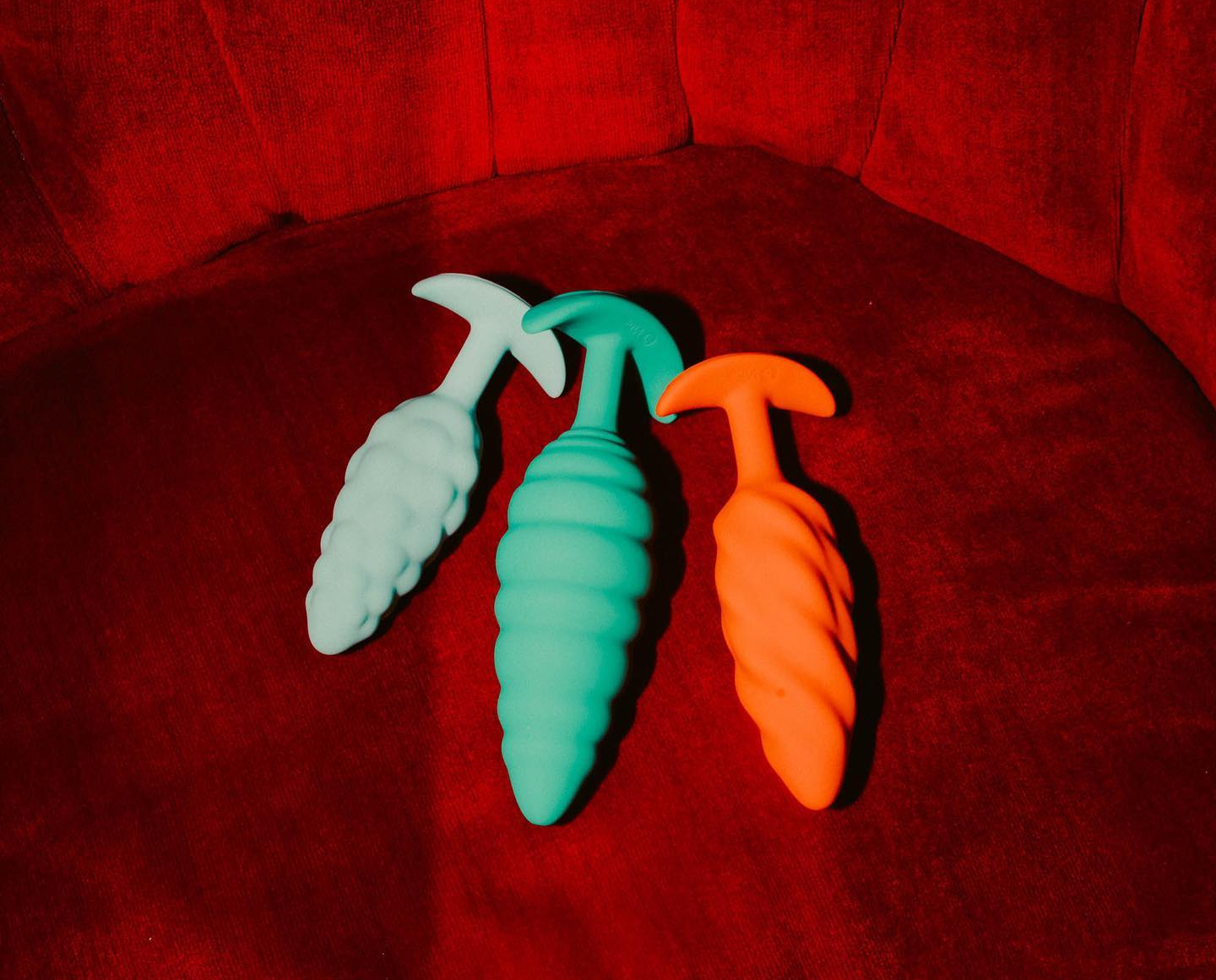 Light blue, green and orange butt plug side by side for size comparison