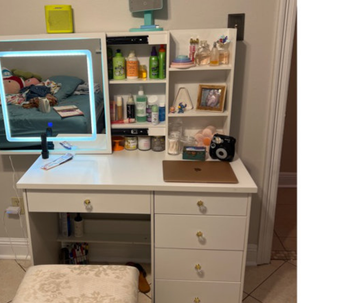 reviewer photo of light-up vanity, full of makeup and hair products
