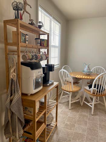 A room  country   with a woody  support  holding room  appliances, hanging cups, and a array  with 4  chairs and a floral teapot