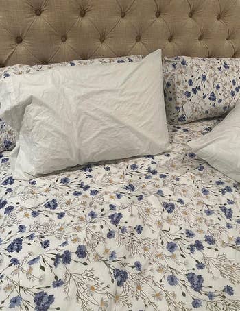 Bed with white and blue floral bedding and a tufted headboard