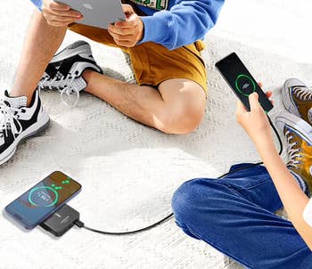 Two radical   sitting connected  the level  utilizing powerfulness  banks to complaint  their smartphones and tablets, illustrating portable charging solutions