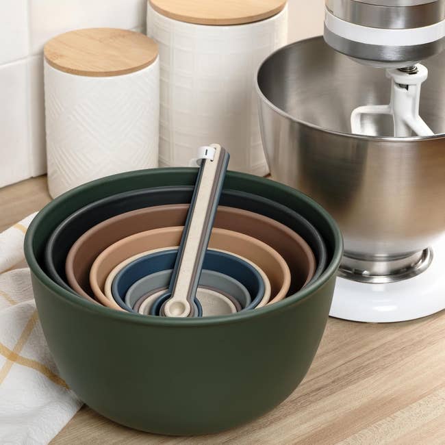 Nested mixing bowls with measuring spoons beside a basal   mixer connected  a room  countertop