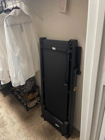 reviewer photo of a black treadmill folded against the wall of their closet