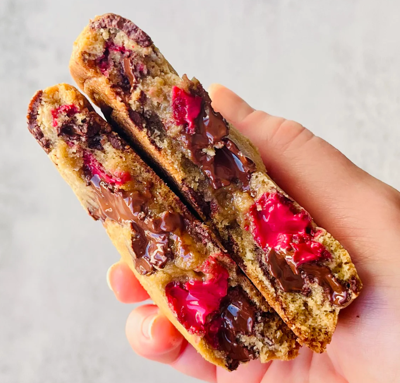 person holding chocolate-dipped berries cookies from seven grams caffe