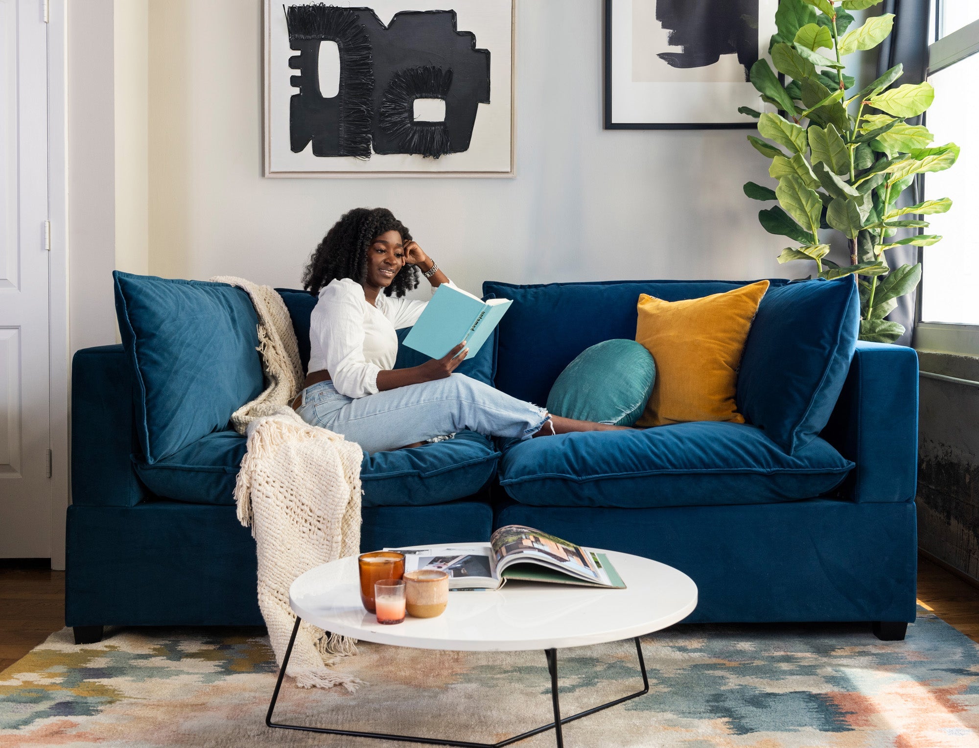 model reading and lounging on the velvet blue kova sofa