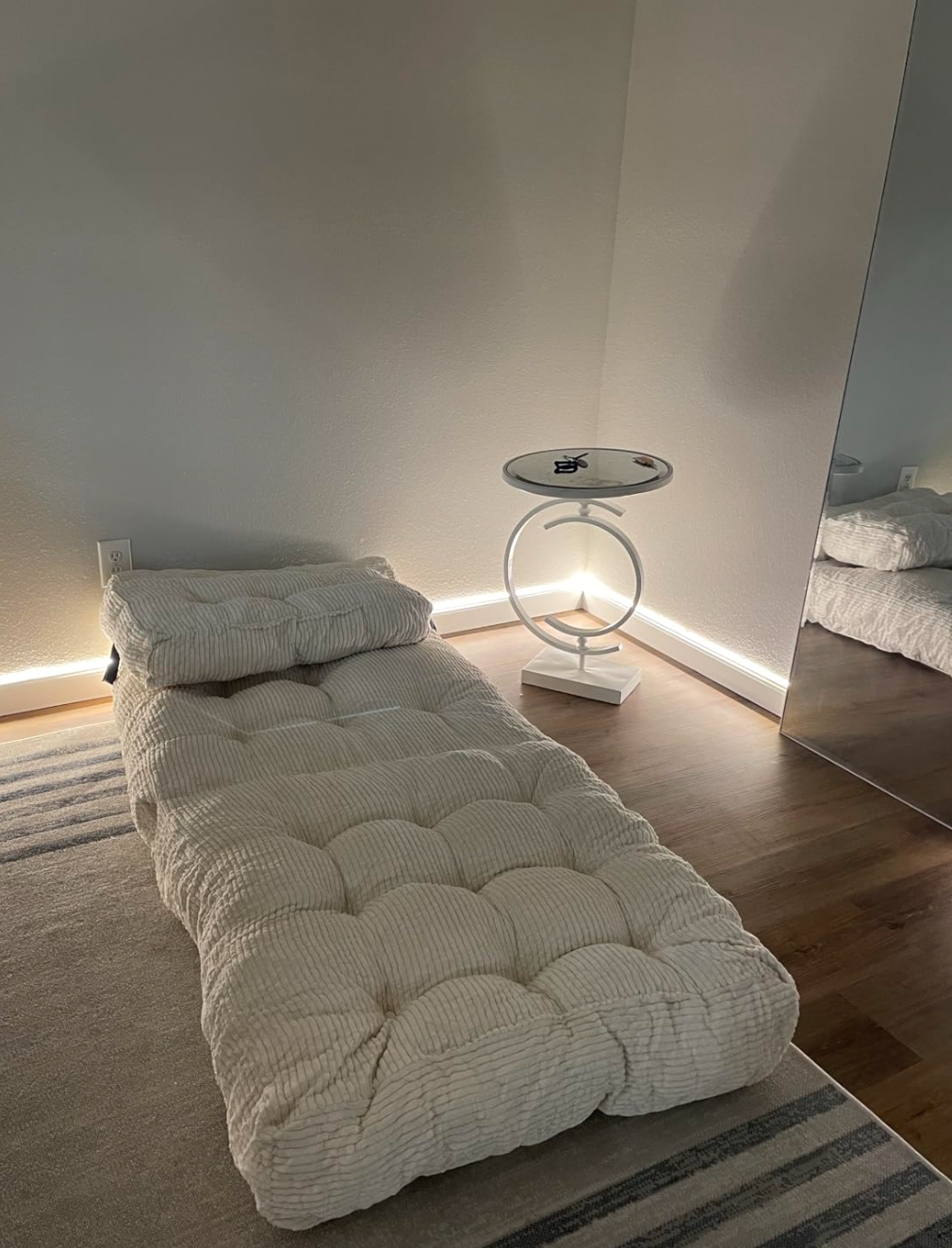 Minimalist room with a plush daybed and a modern circular side table, reflecting a cozy shopping aesthetic