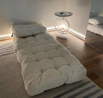 Minimalist room with a plush daybed and a modern circular side table, reflecting a cozy shopping aesthetic