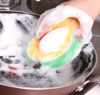 A model cleaning a pan with a soapy avocado shaped sponge 