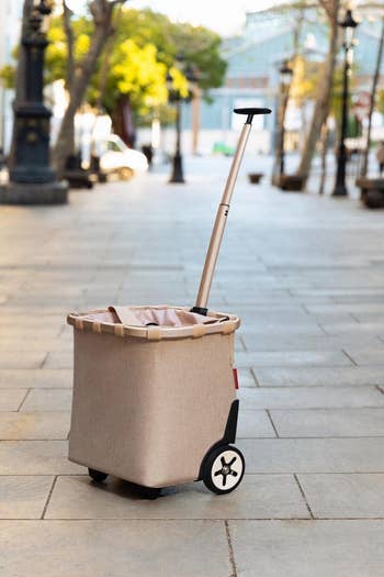 Portable pink cart with extendable handle on a sidewalk 