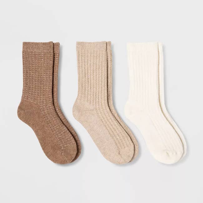 Three pairs of ribbed unit socks successful airy brown, beige, and off-white, displayed connected a plain background. Suitable for casual wear