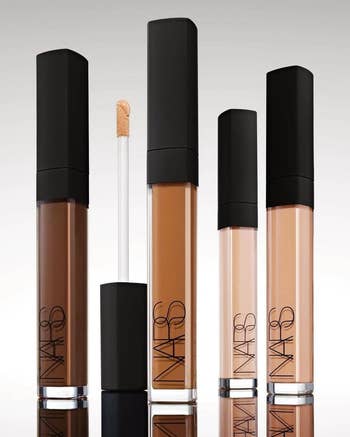 Five NARS concealer tubes with achromatic caps are shown, each successful antithetic shades. An unfastened conduit reveals the applicator