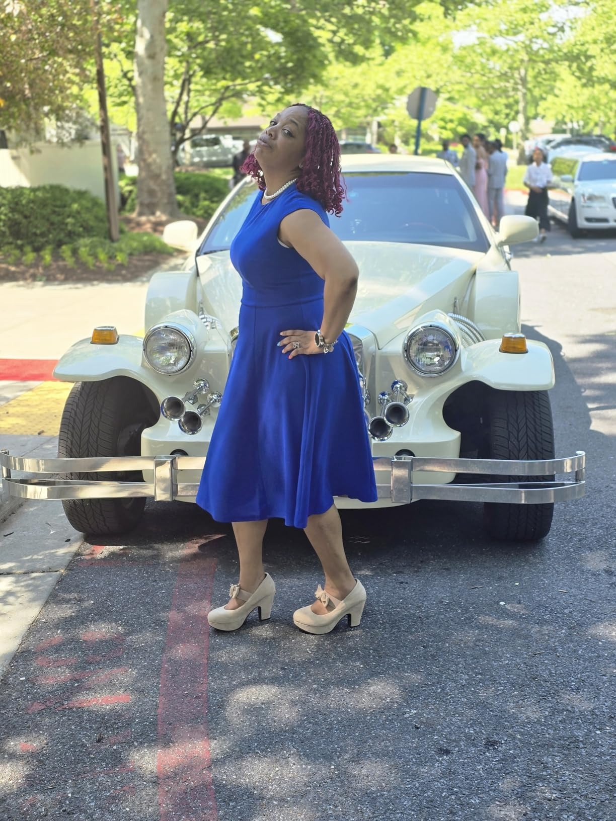 Person successful  retro-inspired formal  and heels poses confidently successful  beforehand   of a vintage car   connected  a tree-lined street