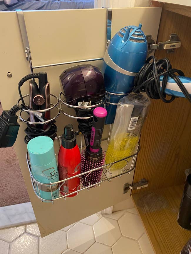 hair tool organizer attached to the cabinet door, holding hot tools, products, and a round brush