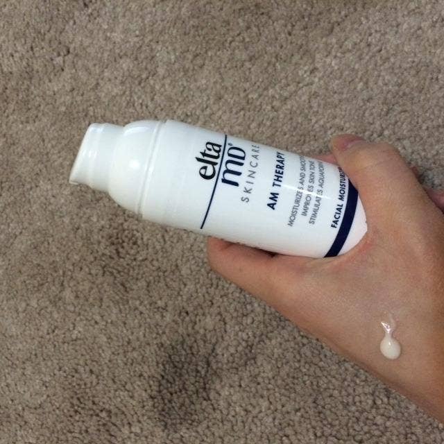 reviewer holding moisturizer bottle with some on hand