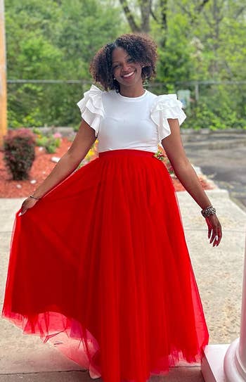 Another reviewer in the white ruffle sleeve bodysuit with a red skirt