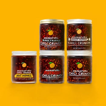 five glass jars of different chili crunches