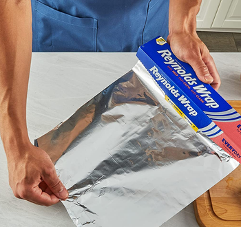person tearing off piece of foil for use in kitchen