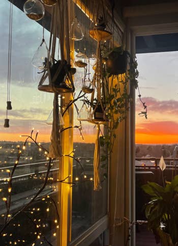 A cozy balcony at sunset with hanging plants, string lights, and a clear view of the sky, ideal for home decor inspiration