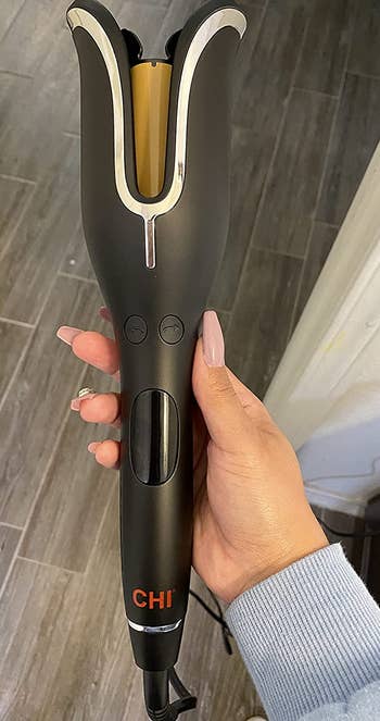 A reviewer holding their Chi curling tool